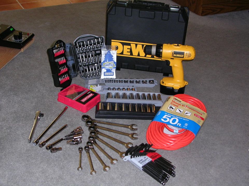 Collection of tools including a DeWalt drill, socket sets, wrenches, and extension cord