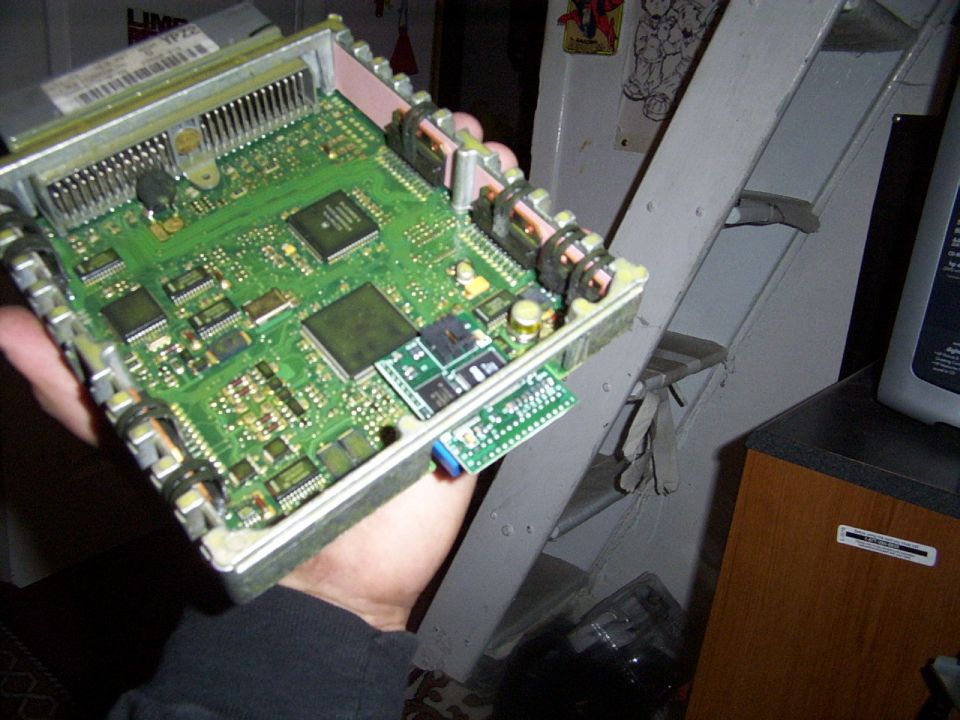 Hand holding an engine control unit circuit board with many chips and connectors