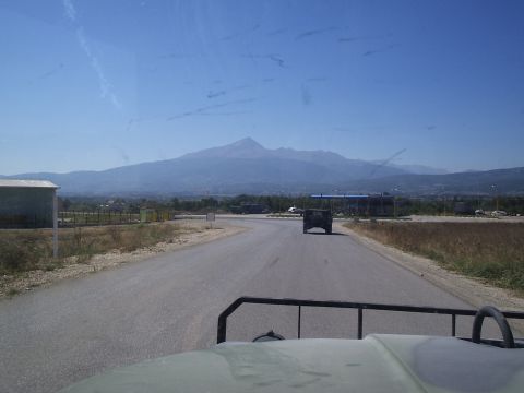 1996 Ford Bronco - A dark SUV is seen from the perspective of another vehicle on a road with a mountain range in the distance.