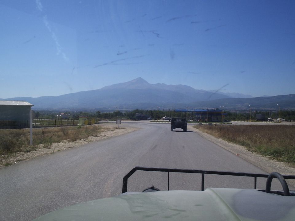 Dark SUV driving on a road with mountains in the background