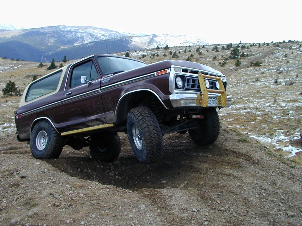 Brown 1978 Ford Bronco with a white top and yellow brush guard on a dirt hill