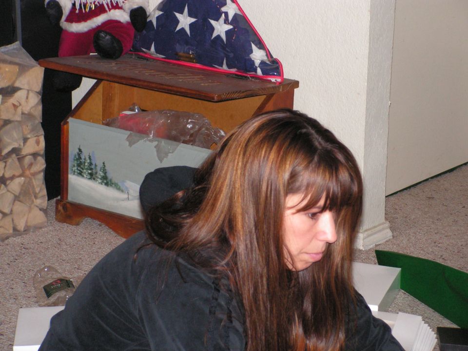 Woman with long brown hair looking down in a living room near a wooden chest