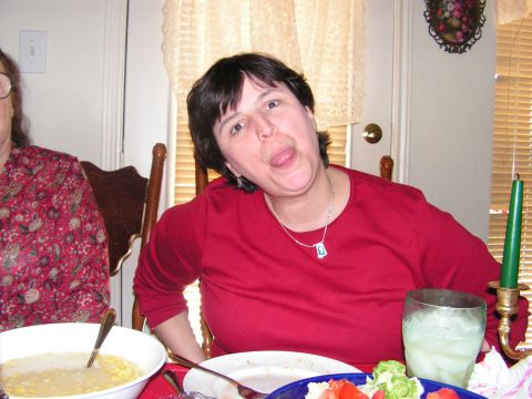 1978 Ford Bronco - A woman playfully sticks her tongue out while sitting at a table set for a meal.