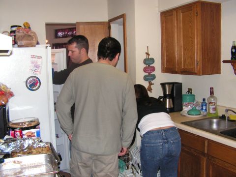 1978 Ford Bronco - Three people are in a kitchen, with two looking into an open refrigerator.