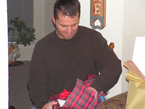 1978 Ford Bronco - A man unwraps a holiday gift, revealing a red plaid paper and bow.