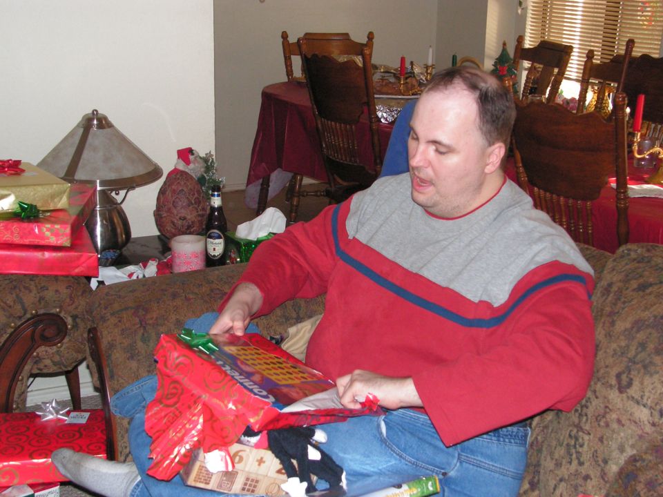 Man opening Christmas gifts, Supermotors.net logo visible