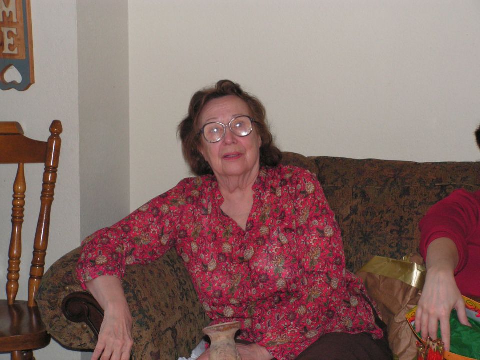 woman with glasses and floral shirt sitting on a couch