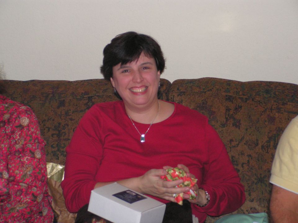 Woman in red shirt sitting on a couch, holding a small gift