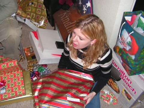 1978 Ford Bronco - A woman sits on the floor surrounded by Christmas gifts, holding a large present wrapped in red and gold stripes.