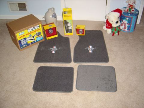 1986 Ford Bronco - Ford Mustang floor mats and car parts are laid out on a carpeted floor.