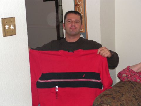 1978 Ford Bronco - A man holds up a red and black striped sweater in front of a wall and doorway.