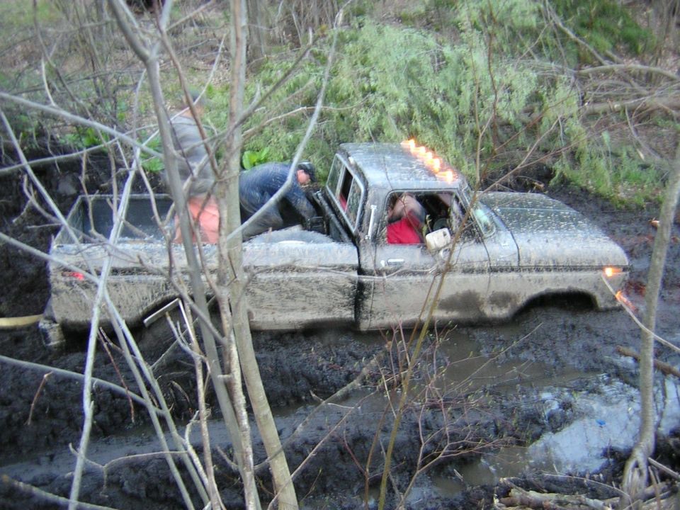 1978 Ford F-250 stuck in mud with two people inside, one in driver's seat, other leaning over from passenger side