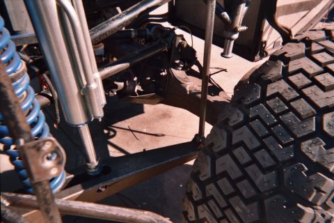 1990 Ford Bronco - Close view of a tube-framed vehicle's blue coil springs and shock mounts next to an off-road tire on concrete.