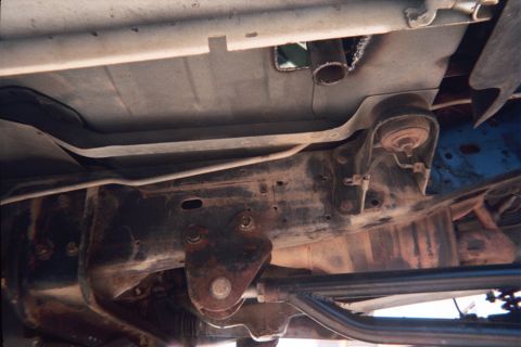 1990 Ford Bronco - Underbody view of a truck showing frame rails, a fuel tank, exhaust pipe and transmission crossmember.