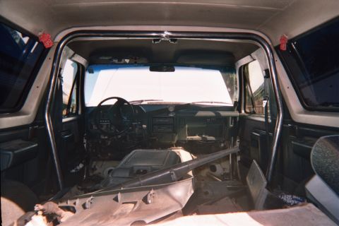 1990 Ford Bronco - View through a gutted SUV interior toward the steering wheel and dash with floor pans exposed and seats removed.