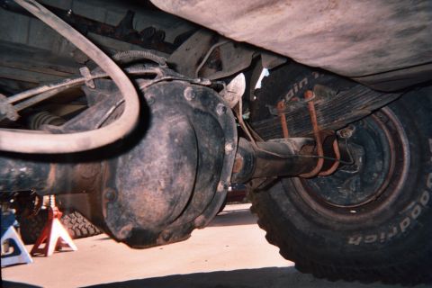 1990 Ford Bronco - Undercarriage shot of a solid front axle, round differential housing and leaf spring beside a BFGoodrich off-road tire.