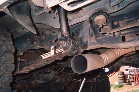 1990 Ford Bronco - Undercarriage view showing a stacked leaf spring pack, frame rails and a large diameter angled exhaust outlet.
