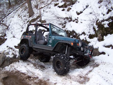 1985 Ford Bronco - A modified Jeep Wrangler navigates a challenging snowy terrain with large tires and a lifted suspension.
