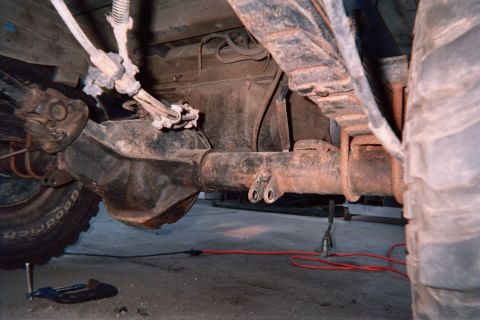 1990 Ford Bronco - Underbody view of a 4x4's front axle and differential with the exhaust pipe routed alongside, jack stands beneath.