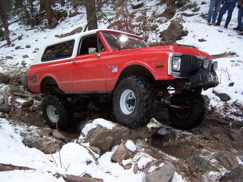 1985 Ford Bronco - This lifted SUV is shown off-roading in a snowy, rocky environment.