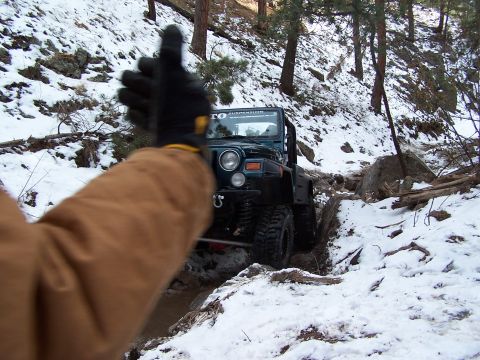 1985 Ford Bronco - Jeep Wrangler off-roading on a snowy mountain trail.