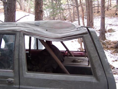 1985 Ford Bronco - The roof of an SUV shows significant damage, with a roll cage visible through the windows.