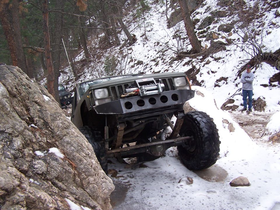 Olive green off-road SUV navigating rocky, snowy terrain