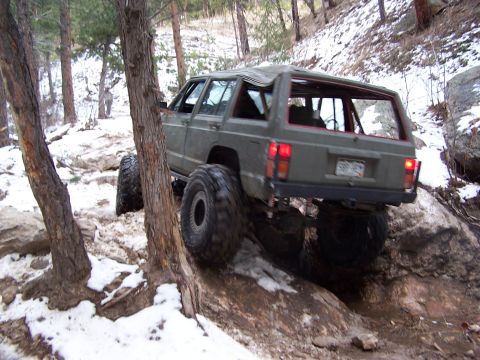 1985 Ford Bronco - Jeep Cherokee XJ tackling rough terrain on a snowy day.