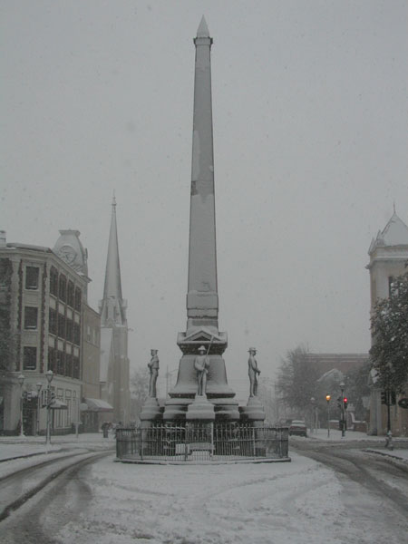 1988 Ford Bronco - A monument stands in a snow-covered town square, with buildings and a church spire visible in the background.