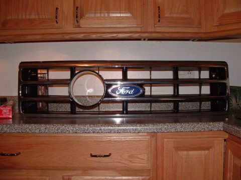 1990 Ford Bronco - A Ford grille with the blue oval emblem is displayed on a countertop.
