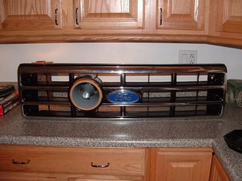 1990 Ford Bronco - A chrome-and-black Ford truck grille with the blue oval Ford emblem, propped on a granite kitchen counter in front of oak cabinets. A round…