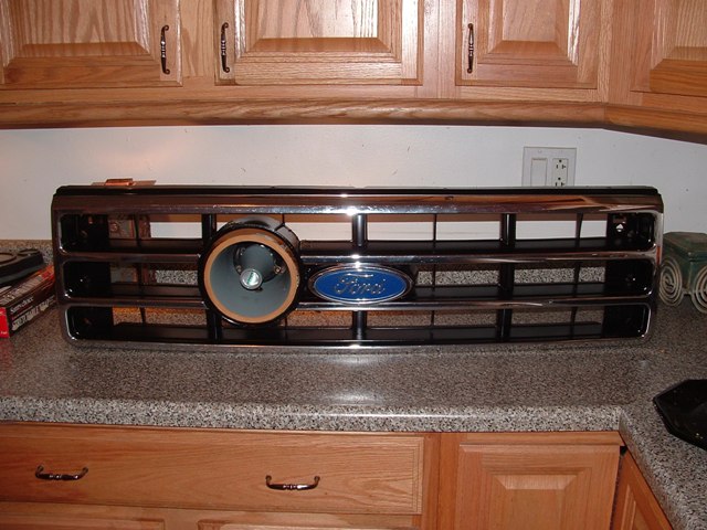 Chrome Ford grille with blue oval emblem and a round lamp fitted in the left opening, on a kitchen counter