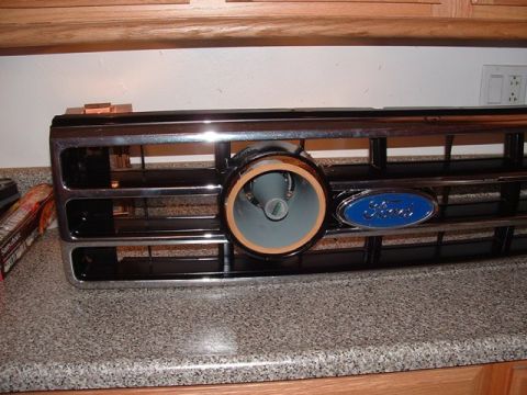 1990 Ford Bronco - Angled view of a chrome-trimmed black Ford truck grille resting on a granite kitchen counter with a round car speaker fitted into the cente…