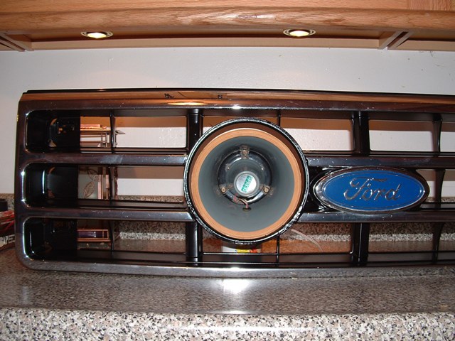 Ford truck grille with a speaker mounted in the round center opening next to the blue Ford oval