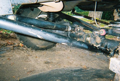 1978 Ford Bronco - Close-up view of the suspension system and a tire on a vehicle's undercarriage.