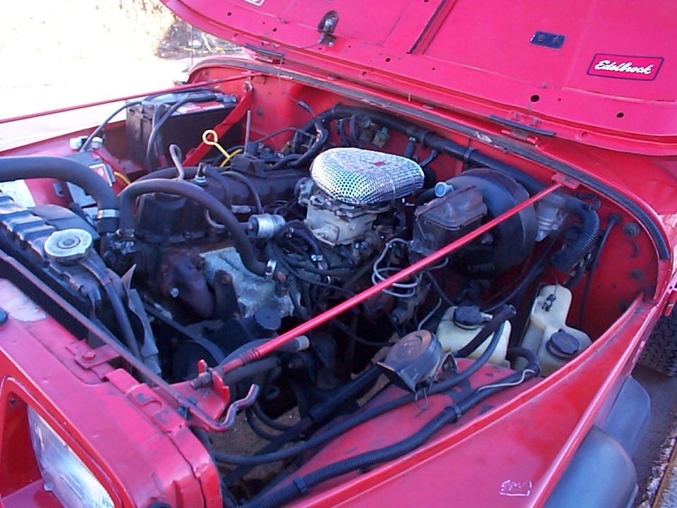 Red 1989 Jeep YJ engine bay with Edelbrock sticker
