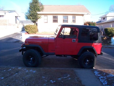 1989 Jeep YJ - Side view of a red 1989 Jeep YJ with a black soft top.