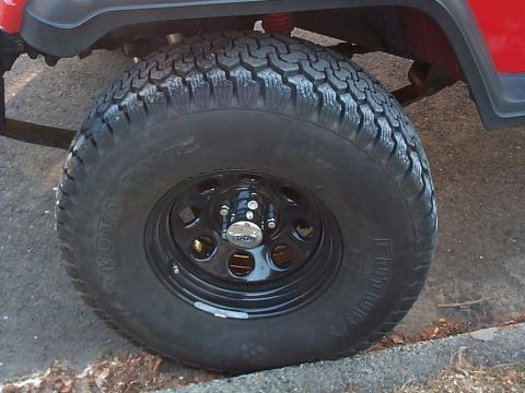 1989 Jeep YJ - Close-up of a red 1989 Jeep YJ's side, a black wheel with a Futura Dakota tire.