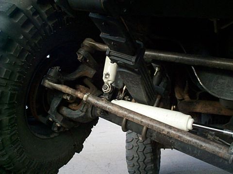1994 Ford Bronco - The underside of an off-road vehicle, focusing on the front suspension components and a large tire.