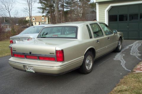 2001 Ford Crown Victoria - Rear view of a gold Lincoln Town Car parked in a driveway next to a silver BMW.