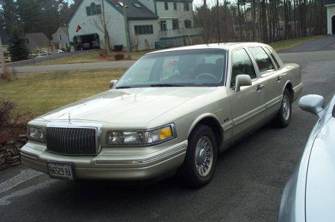 2001 Ford Crown Victoria - This gold Lincoln Town Car is parked in a driveway, showing its front 3/4 view.