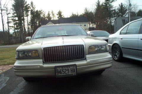 2001 Ford Crown Victoria - A gold Lincoln Town Car is parked in a driveway with another vehicle visible behind it.
