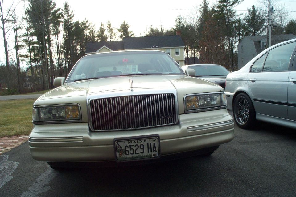 Gold Lincoln Town Car parked in driveway, another car behind it