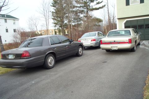 2001 Ford Crown Victoria - A dark gray 2001 Ford Crown Victoria is parked in a driveway with two other vehicles.