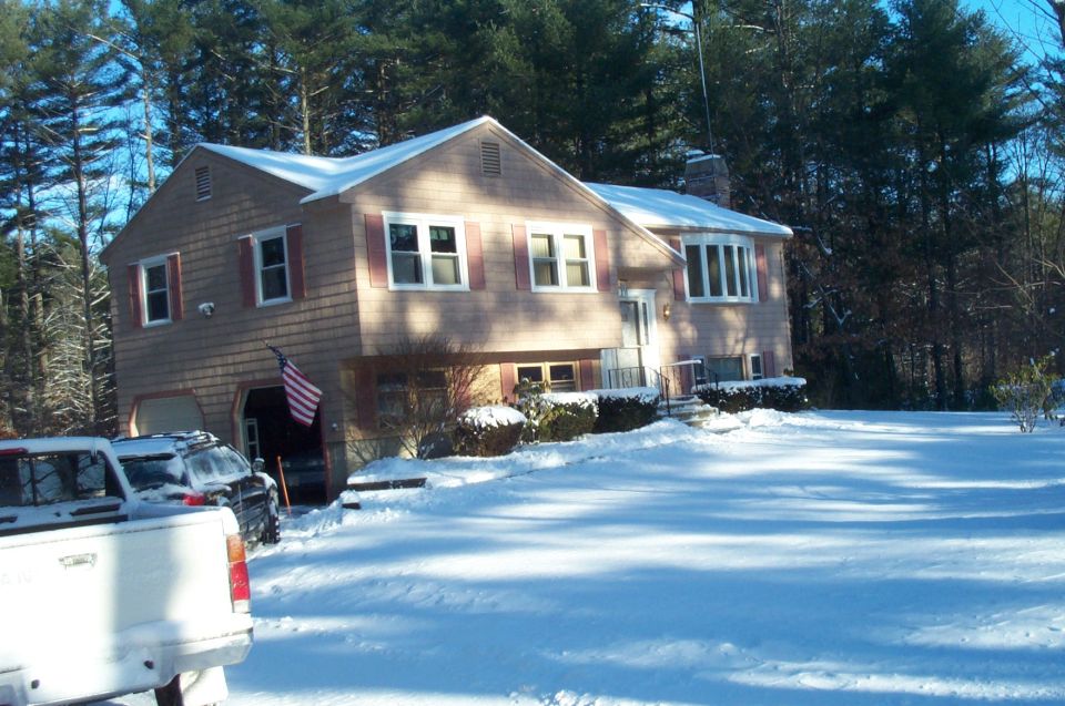 House covered in snow with two vehicles in the driveway