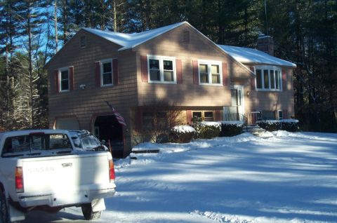 2001 Ford Crown Victoria - A white Nissan pickup truck is parked in a snowy driveway in front of a house.