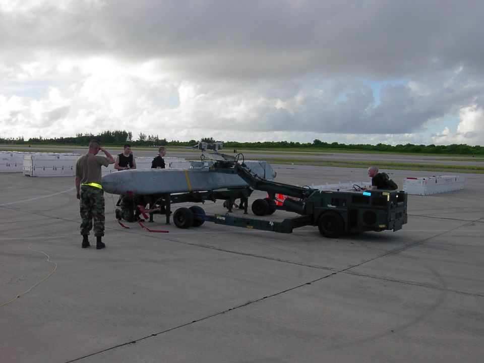 Military A-10 aircraft fuselage on a flatbed loader being moved by airmen on a flightline