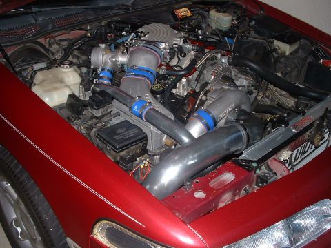 1992 Ford Crown Victoria - Custom turbocharger system installed in a vehicle's engine bay, polished metal piping and blue hose clamps.