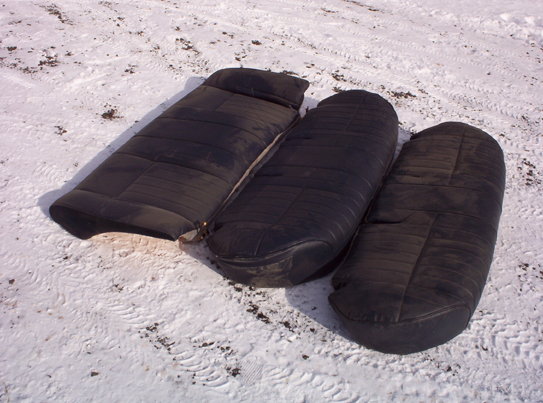 Three black car seats laid out on snowy ground
