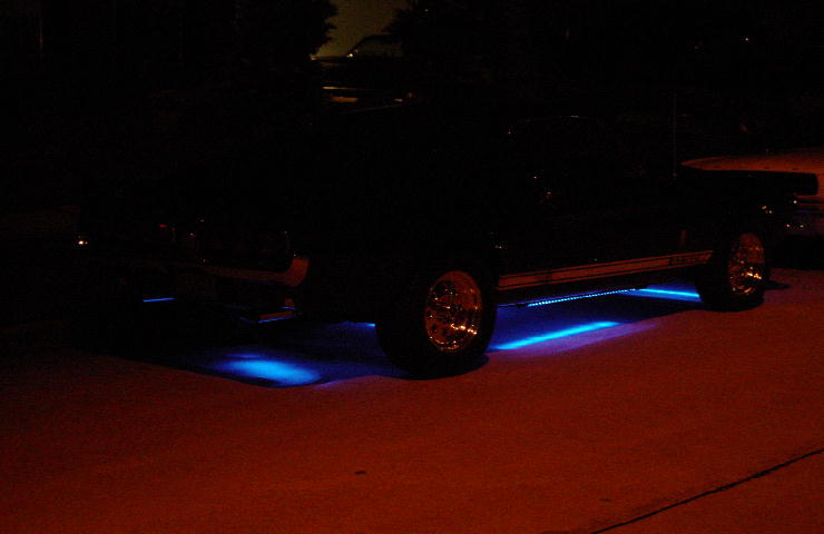 Side profile of truck at night with blue underglow lighting the pavement beneath it
